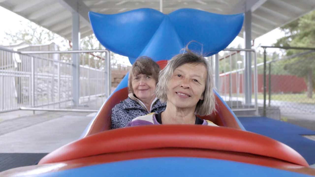 two women sitting on a fish themed carnival ride